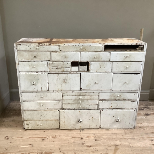 84 - A late 19th/early 20th century set of chemist drawers in pine painted white, having numerous sized d... 