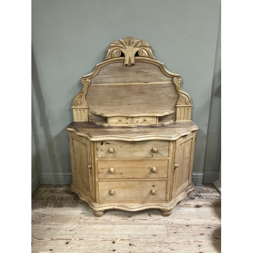 88 - A Victorian stripped pine sideboard having an arched raised back with foliate pediment, two small dr... 