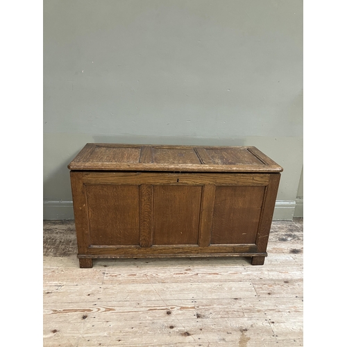 261 - An oak blanket box having a triple indented panel top and conforming front on style feet, 108cm x 46... 