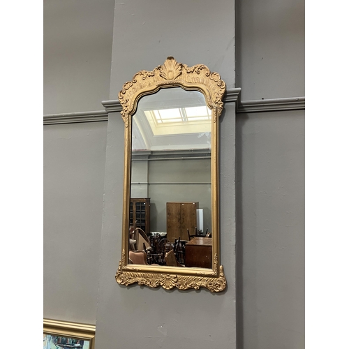 264 - A gilt framed wall mirror of arched outline with foliate moulded pediment, 87cm x 45cm