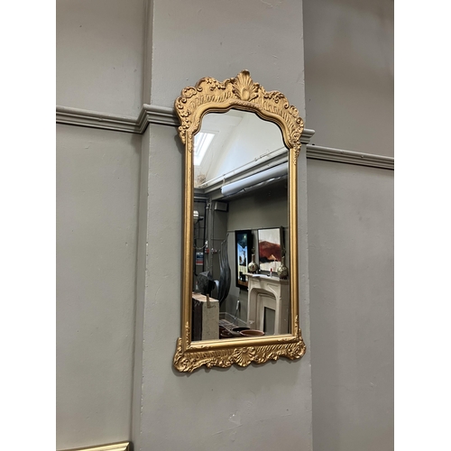 264 - A gilt framed wall mirror of arched outline with foliate moulded pediment, 87cm x 45cm