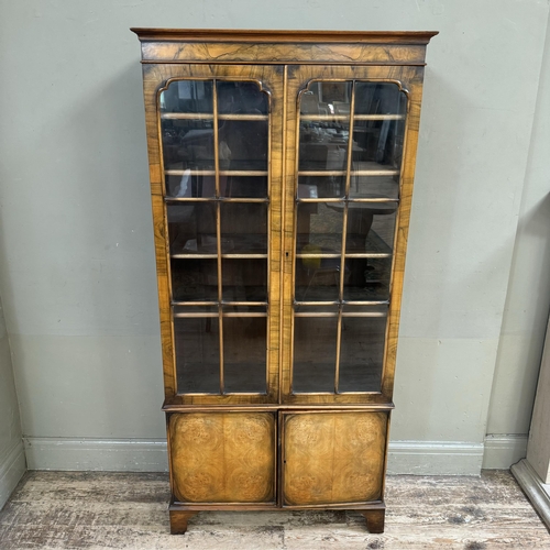 280 - A mid 20th century walnut and glazed bookcase cupboard, having a moulded cornice above two tracery g... 