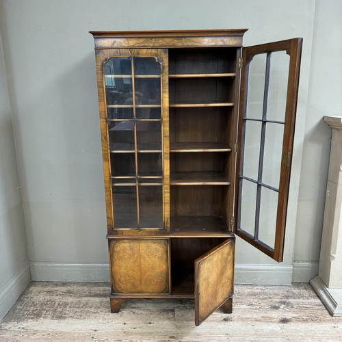 280 - A mid 20th century walnut and glazed bookcase cupboard, having a moulded cornice above two tracery g... 