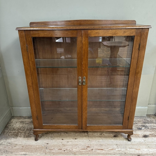 281 - A mahogany and glazed book case cupboard with a short raised back and on short cabriole legs, 114cm ... 