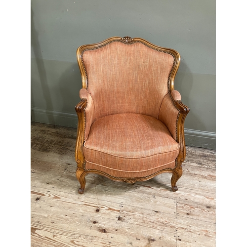 284 - A reproduction French bergere style armchair having a moulded and encircling frame, floral cresting,... 