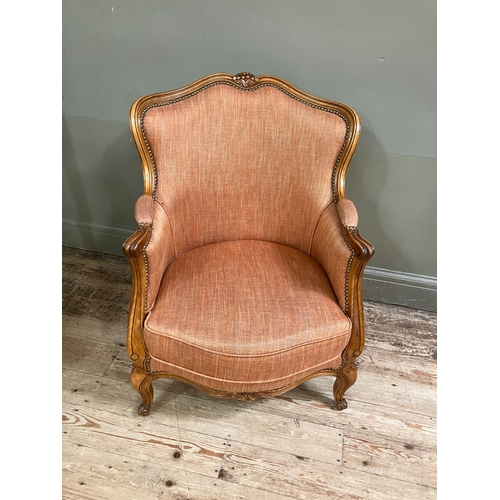 284 - A reproduction French bergere style armchair having a moulded and encircling frame, floral cresting,... 