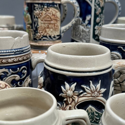 136 - A large quantity of German pottery steins glazed in blue and with relief moulded scenes