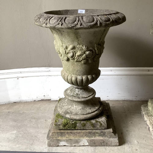 230 - A cast garden urn having an egg and dart rim, foliate border and lower lobed body on a bladed socle ... 