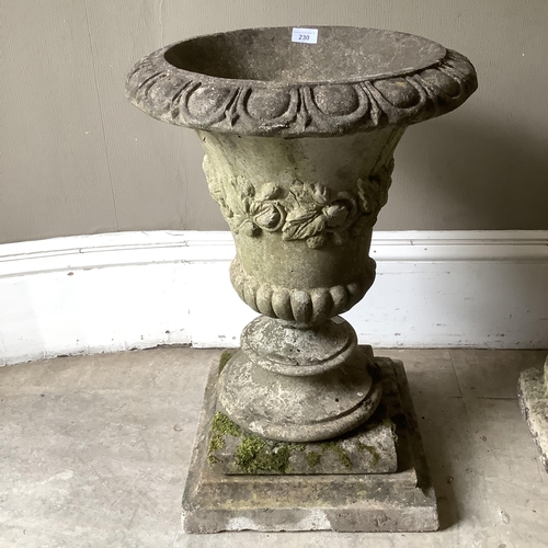 230 - A cast garden urn having an egg and dart rim, foliate border and lower lobed body on a bladed socle ... 