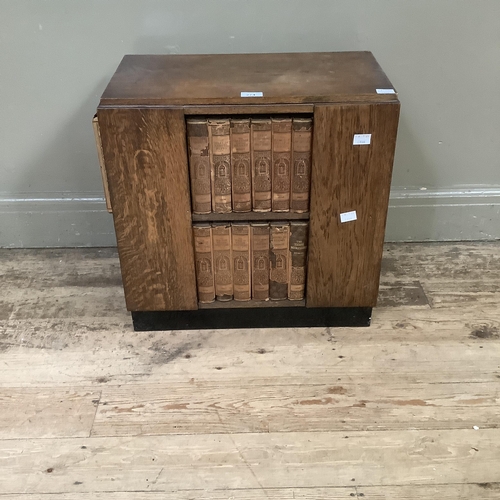 274 - An art deco oak bookcase with compartments to each side on a plinth base and holding a set of unifor... 