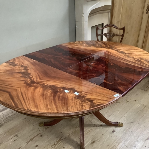 295 - A figured mahogany quarter veneered circular extending dining table on a tripod base with reeded leg... 