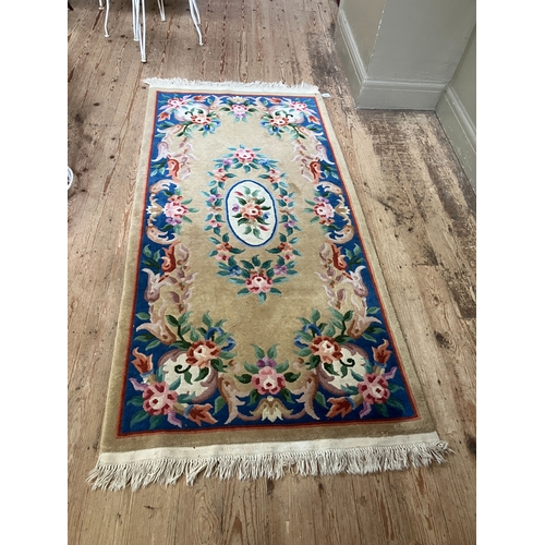 299 - A Chinese wool rug of blue, rose, green, ivory and camel in a floral design