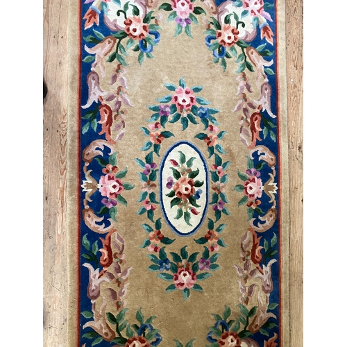 299 - A Chinese wool rug of blue, rose, green, ivory and camel in a floral design