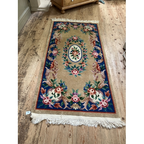 299 - A Chinese wool rug of blue, rose, green, ivory and camel in a floral design