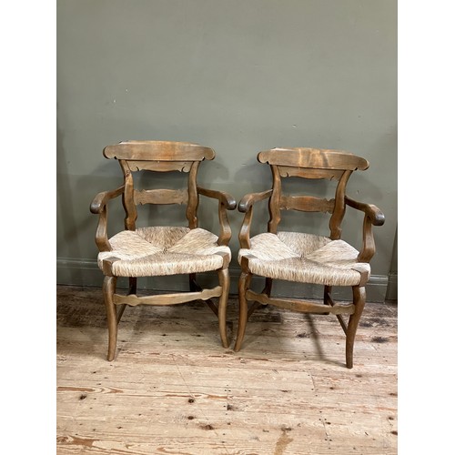 283 - A pair of 19th century continental fruitwood kitchen armchairs having a shaped top rail and tie rail... 