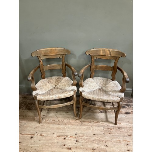 283 - A pair of 19th century continental fruitwood kitchen armchairs having a shaped top rail and tie rail... 