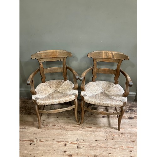 283 - A pair of 19th century continental fruitwood kitchen armchairs having a shaped top rail and tie rail... 