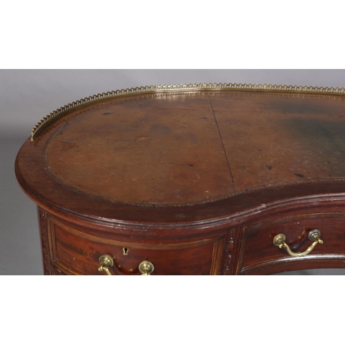 479 - A MAHOGANY KIDNEY SHAPE DESK circa 1920s, having a pierced brass gallery and leather incised writing... 