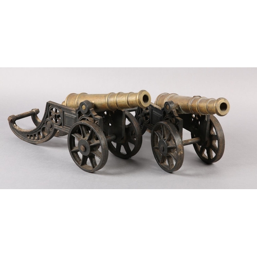 174 - A PAIR OF BRASS AND CAST IRON models of canons, with ribbed barrels, 47cm wide