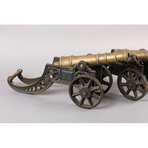 174 - A PAIR OF BRASS AND CAST IRON models of canons, with ribbed barrels, 47cm wide