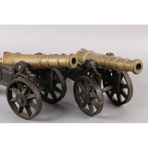 174 - A PAIR OF BRASS AND CAST IRON models of canons, with ribbed barrels, 47cm wide