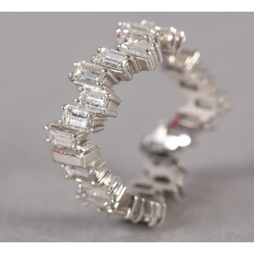 378 - A DIAMOND SET BAND RING, c1960, the baguette cut stones claw set in wave form, in white metal (tests... 