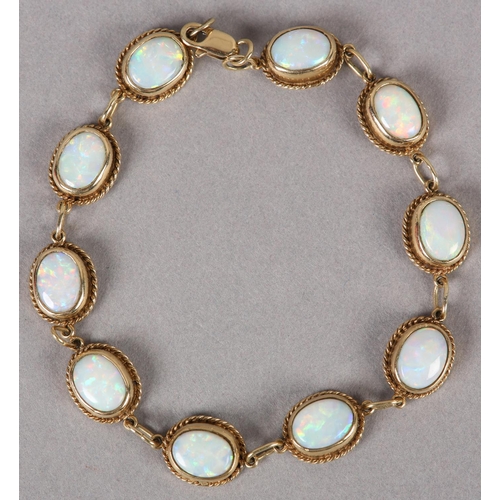 375 - AN OPAL BRACELET in 9ct gold, each link collet set with an oval cabochon stone within a twisted wire... 