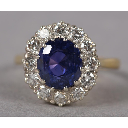 348 - A SAPPHIRE AND DIAMOND CLUSTER RING c1974 in 18ct gold and white gold, claw set to the centre with a... 