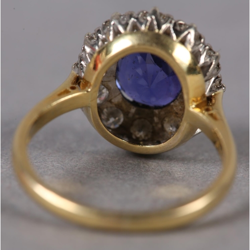 348 - A SAPPHIRE AND DIAMOND CLUSTER RING c1974 in 18ct gold and white gold, claw set to the centre with a... 