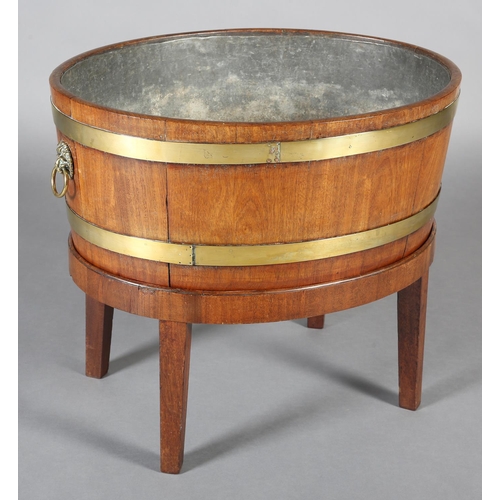 474 - A GEORGE III MAHOGANY AND BRASS BOUND WINE COOLER, of oval outline with lion mask and ring handles, ... 