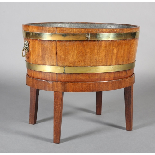 474 - A GEORGE III MAHOGANY AND BRASS BOUND WINE COOLER, of oval outline with lion mask and ring handles, ... 