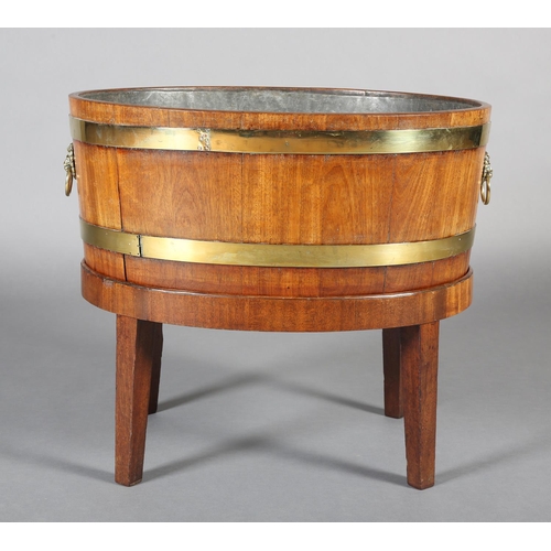 474 - A GEORGE III MAHOGANY AND BRASS BOUND WINE COOLER, of oval outline with lion mask and ring handles, ... 