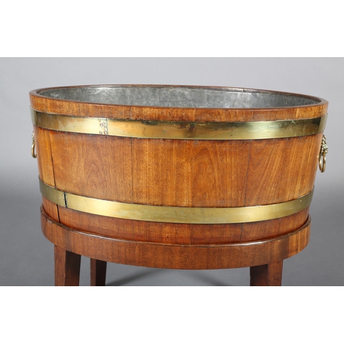 474 - A GEORGE III MAHOGANY AND BRASS BOUND WINE COOLER, of oval outline with lion mask and ring handles, ... 