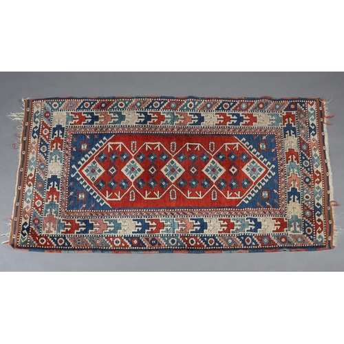 449 - A CAUCASIAN KAZAK RUG, the blue field having a red panel filled with five diamond shape motifs and r... 