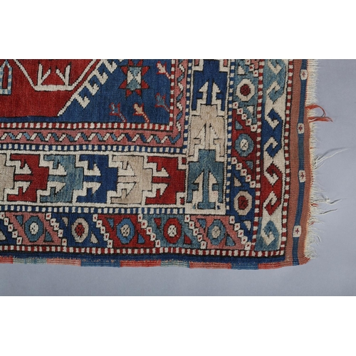 449 - A CAUCASIAN KAZAK RUG, the blue field having a red panel filled with five diamond shape motifs and r... 