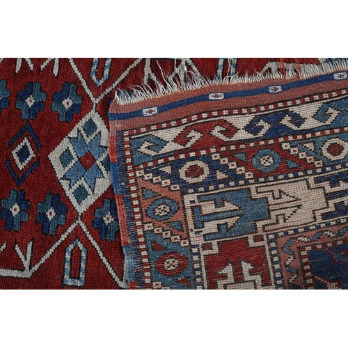 449 - A CAUCASIAN KAZAK RUG, the blue field having a red panel filled with five diamond shape motifs and r... 