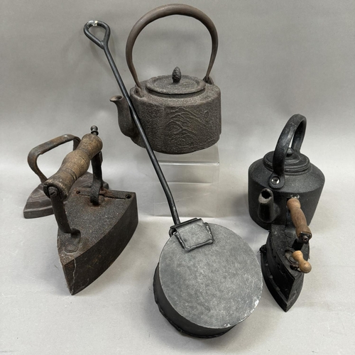 141 - Three cast iron irons, two kettles and a chestnut roster