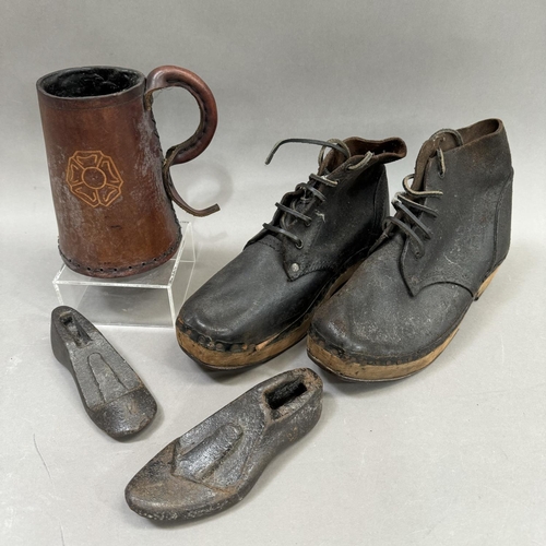 126 - A pair of wooden soled lace up shoes, a pair of cast iron shoe stretchers and a leather drinking ves... 