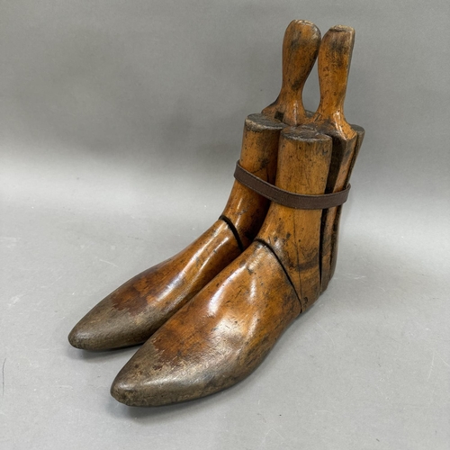 23 - A pair of carved wooden treen adjustable shoe lasts, held together with leather belt