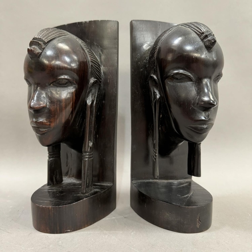 30 - A pair of ebony Masai bookends carved as tribal faces, 24cm high