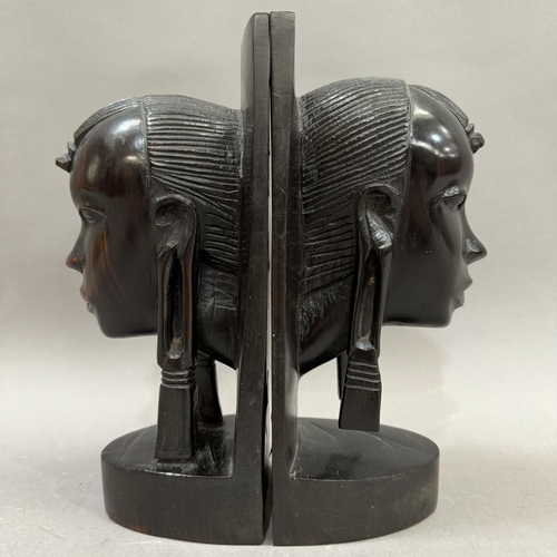 30 - A pair of ebony Masai bookends carved as tribal faces, 24cm high