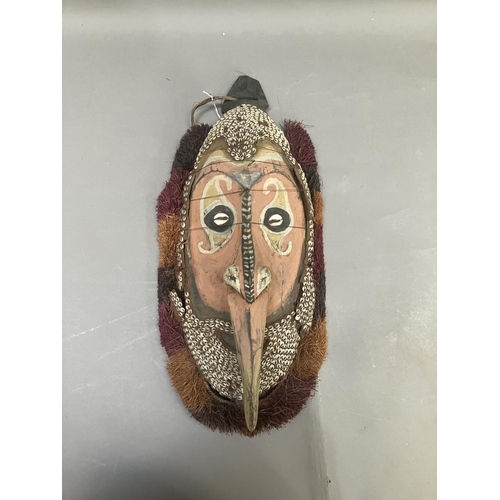 24 - A tribal mask from Papa New Guinea, the face painted and applied with cowrie shells, 51cm high