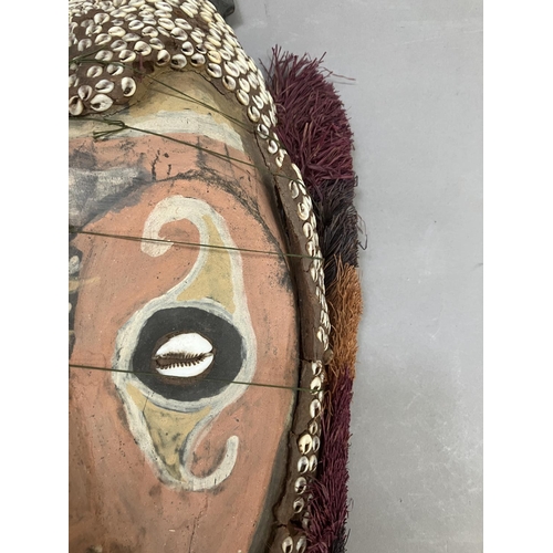 24 - A tribal mask from Papa New Guinea, the face painted and applied with cowrie shells, 51cm high