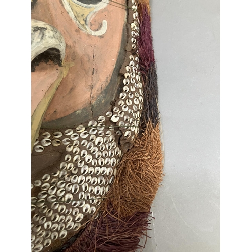 24 - A tribal mask from Papa New Guinea, the face painted and applied with cowrie shells, 51cm high