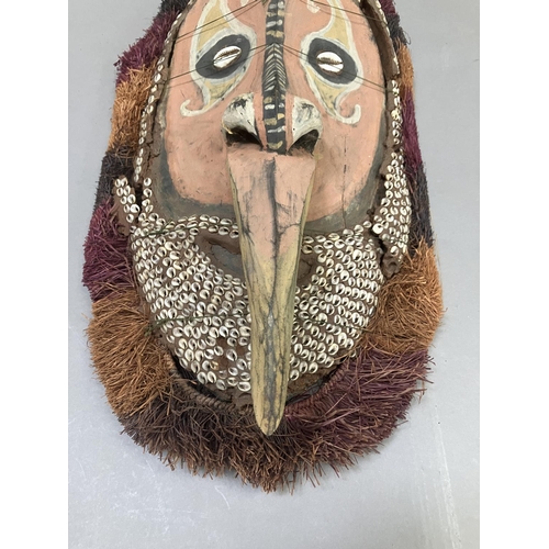 24 - A tribal mask from Papa New Guinea, the face painted and applied with cowrie shells, 51cm high