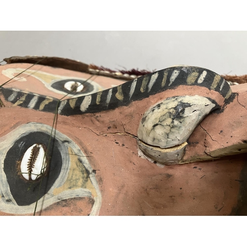 24 - A tribal mask from Papa New Guinea, the face painted and applied with cowrie shells, 51cm high