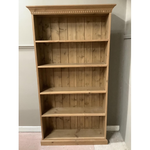 90 - A pine open fronted bookcase with a carved frieze, having four shelves on plinth base 100cm wide