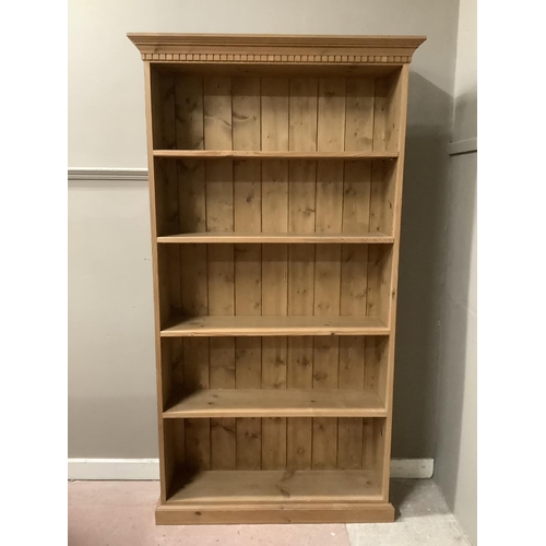 90 - A pine open fronted bookcase with a carved frieze, having four shelves on plinth base 100cm wide