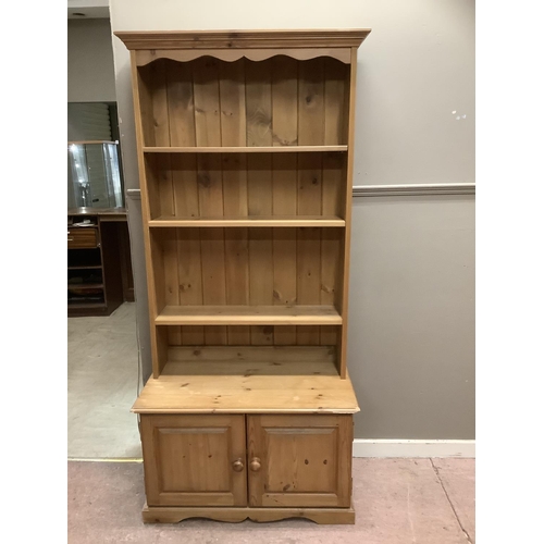 84 - A pine open fronted bookcase cupboard, with three shelves above two doors on plinth base, 91cm wide