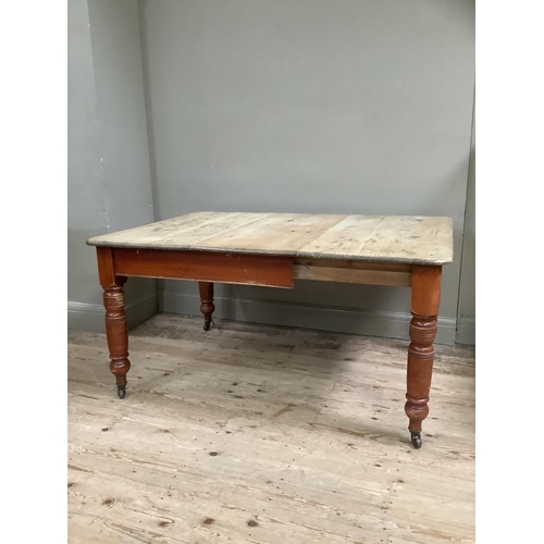 102 - A Victorian stripped pine farmhouse dining table with baluster legs on castors 105cm x 146cm